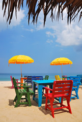 Colorful chair and table with yellow umbrella on the beach