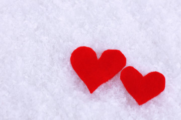 Little felt hearts on snowy background
