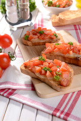 Delicious bruschetta with tomatoes on cutting board close-up