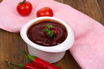 Tomato sauce in bowl on wooden table close-up