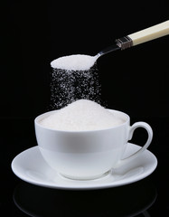 Sugar in cup isolated on black