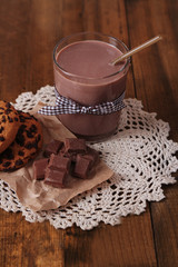 Chocolate milk in glass, on wooden table background