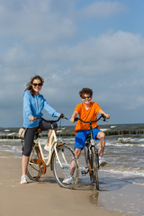 Obraz premium Teenage girl and boy biking on beach