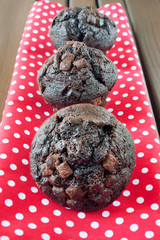 Homemade chocolate muffins on red spotted napkin. Indoors.