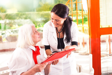 senior woman with a nurse looking at medical report