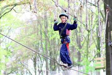 Happy school boy climbing in adventure park