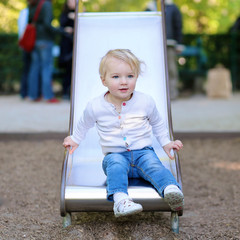 Fototapeta na wymiar Happy toddler girl playing in the park on the slide