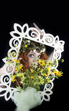 Woman with red hair posing with picture frame and yellow flowers