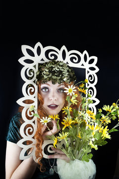 Woman with red hair posing with picture frame and yellow flowers