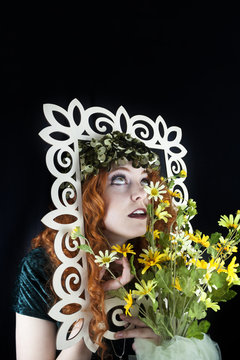 Woman with red hair posing with picture frame and yellow flowers