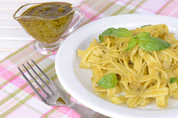 Delicious pasta with pesto on plate on table close-up