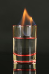 Glass with burning alcohol on black background