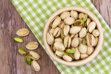 Pistachio nuts in wooden bowl on checkered cloth