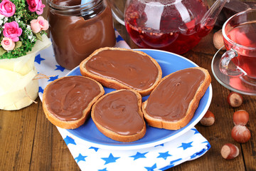Bread with sweet chocolate hazelnut spread on plate on table