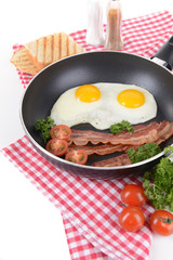 Scrambled eggs and bacon on frying pan on table close-up