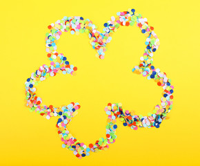 Confetti in shape of flower on yellow background