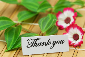 Thank you card with green leaves and daisy flowers on bamboo mat
