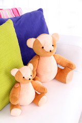 Two bears toy with pillows on sofa