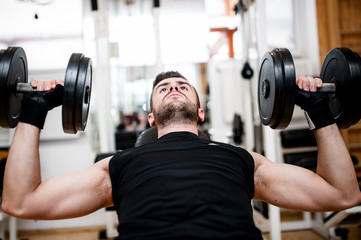 bodybuilder training in the gym: chest - dumbbell bench press