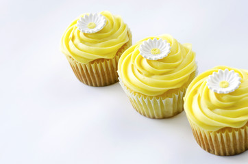 Three yellow cupcakes with daisy decoration