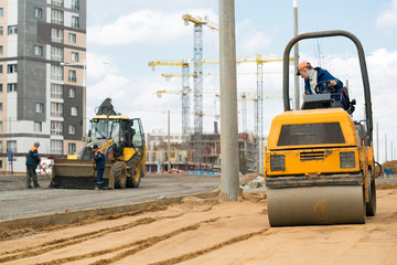 Light tandem vibratory roller compacting sand or soil