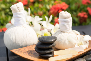 Herbal spa massage with hot compress balls and stacked stones