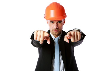 Businessman in hard hat pointing at you over white background