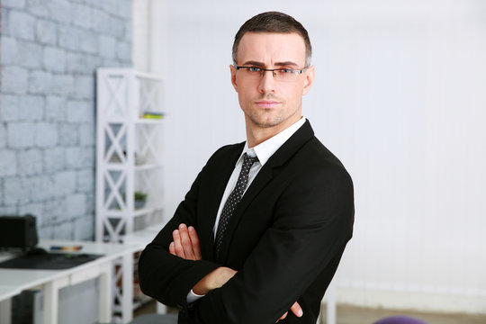 Confident businessman with arms folded standing in office