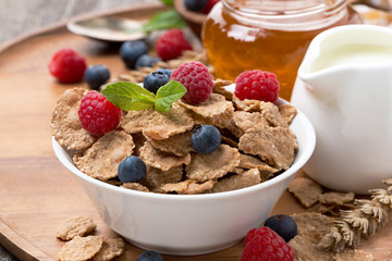 cereal flakes with fresh berries, honey and milk for breakfast