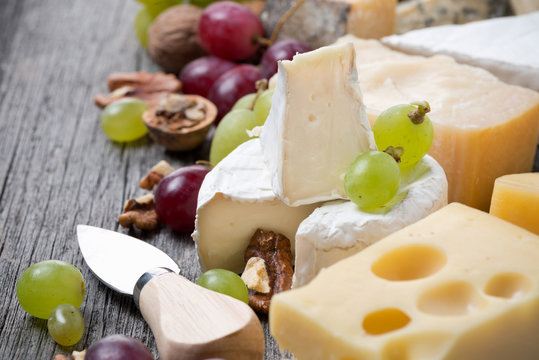 cheeses, grapes and walnuts on a wooden background