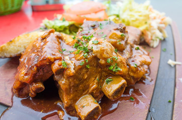 Grilled meat ribs on the plate with hot sauce