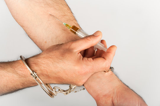 Isolated hype with handcuffs applying injection shot in hand