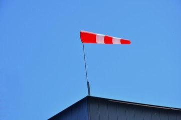 A bright red windsock atop a building