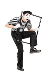 Male mime artist walking through a metal frame