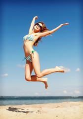 woman in bikini jumping on the beach