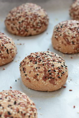 Raw wholegrain buns on the oven-tray before baking