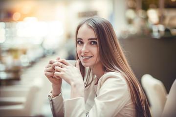 Beautiful smiling woman drinking coffee in cafe