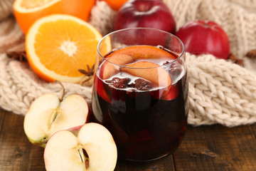 Fragrant mulled wine in glass on knitted scarf close-up