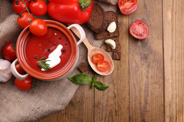 Tasty tomato soup and vegetables on wooden table