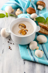 Mushroom soup in white pot, on napkin,  on wooden background