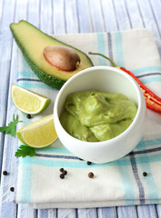 Fresh guacamole in bowl on wooden table