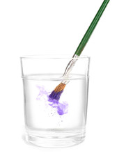 Brush with color paint in glass of water, isolated on white