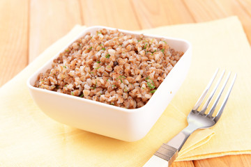 Boiled buckwheat in bowl on table close-up