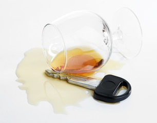 Composition with car key and glass of cognac, isolated on white