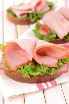 Delicious sandwiches with lettuce and ham on table close-up