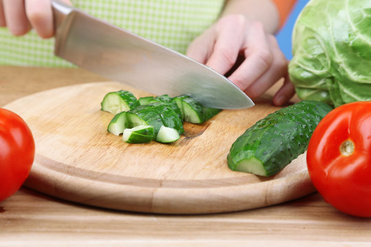 Female hands cutting cucumber