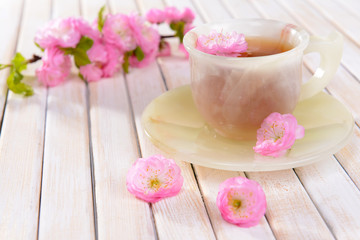 Fototapeta na wymiar Beautiful fruit blossom with cup of tea on table close-up