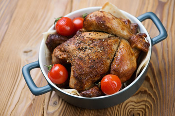 Whole baked chicken with mini tomatoes, studio shot