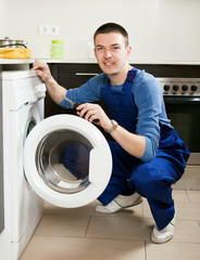 Repairman repairing washing machine at home