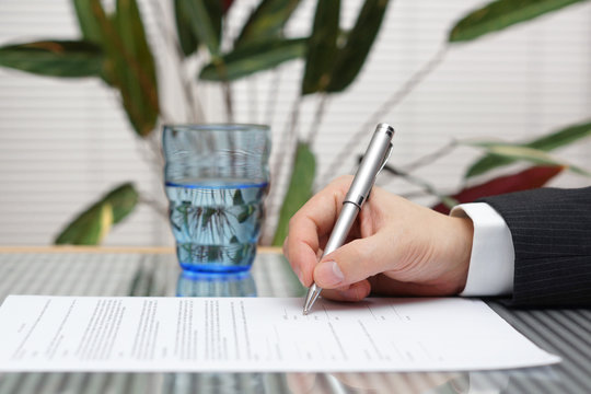 Businessman sitting at office desk signing a contract with shall